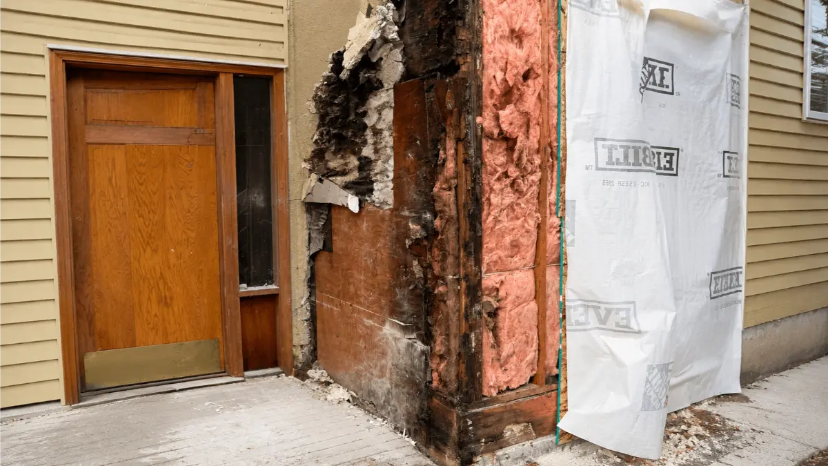 Exposed wall insulation after water damage repair near an entry door