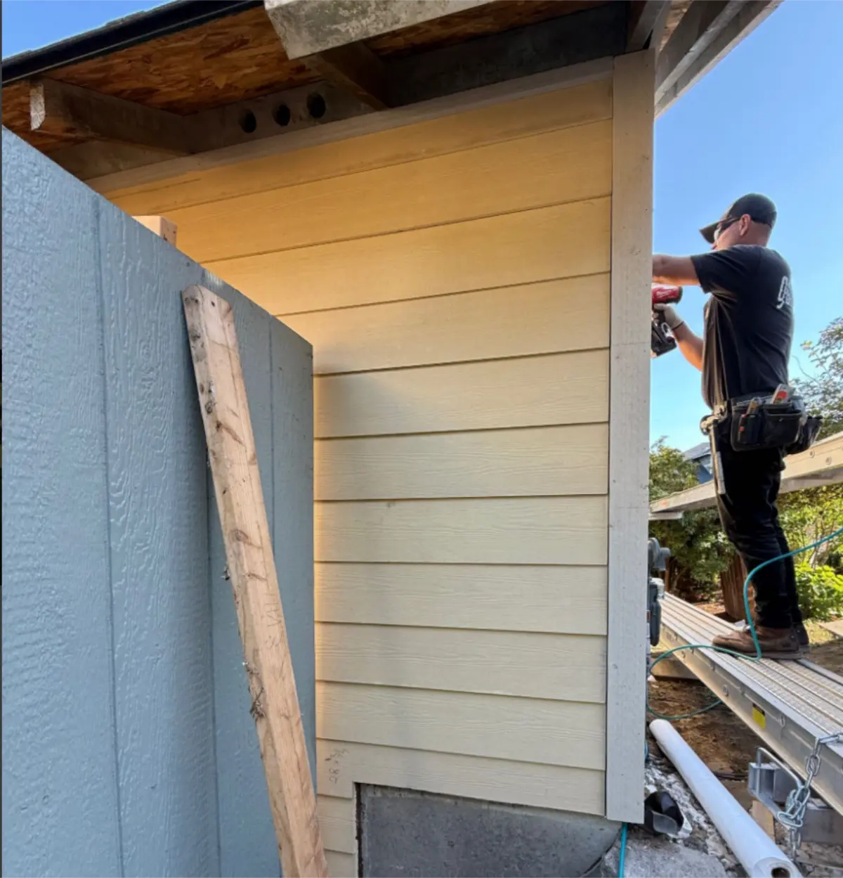 Crew member installing new siding at corner